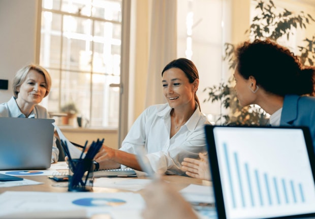 Three businesswomen collaborating in an office setting.